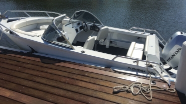 White bowrider boat moored to a wooden dock