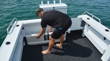 Man placing lounge seat into bracket on back of his boat