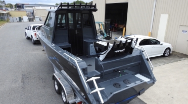 Back of a 7m aluminum boat with a lockable cabin door and bait board